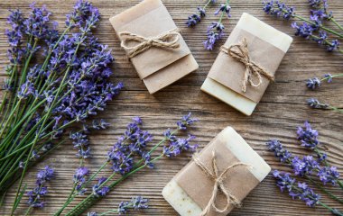 Ahşap arkaplanda lavanta çiçekleri olan el yapımı sabunlar..