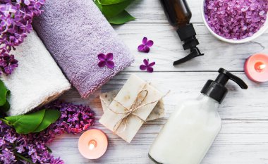 Leylak çiçekli spa seti. Kasede deniz tuzu, aroma yağı şişeleri ve ahşap arka planda mumlar.. 