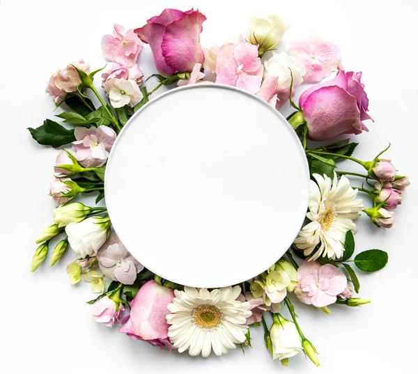 Yuvarlak çerçevede pembe güller ve çiçekler beyaz arkaplanda yazı için beyaz daireler.
