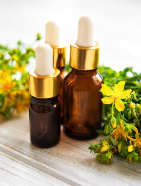 Ahşap masanın üzerinde St. John 's otu özü olan şişeler.