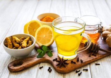 Beyaz ahşap arka planda zerdeçal, zencefil, limon ve bal içeren enerji toniği