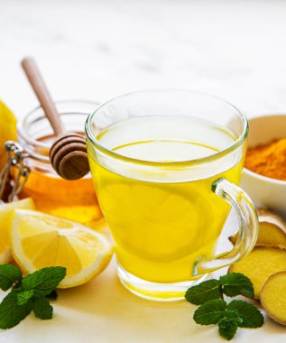 Beyaz mermer bir zemin üzerinde zerdeçal, zencefil, limon ve bal içeren enerji toniği