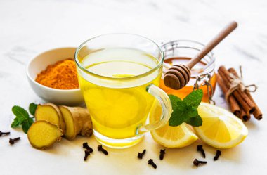 Beyaz ahşap arka planda zerdeçal, zencefil, limon ve bal içeren enerji toniği