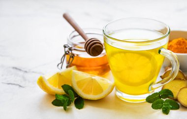 Beyaz ahşap arka planda zerdeçal, zencefil, limon ve bal içeren enerji toniği