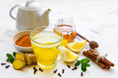 Beyaz ahşap arka planda zerdeçal, zencefil, limon ve bal içeren enerji toniği