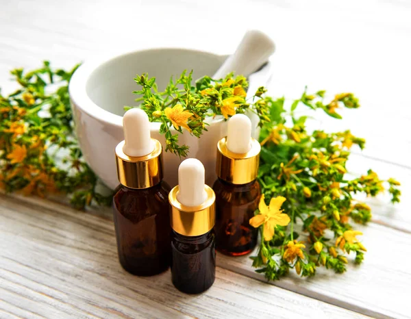 Ahşap masanın üzerinde St. John 's otu özü olan şişeler.