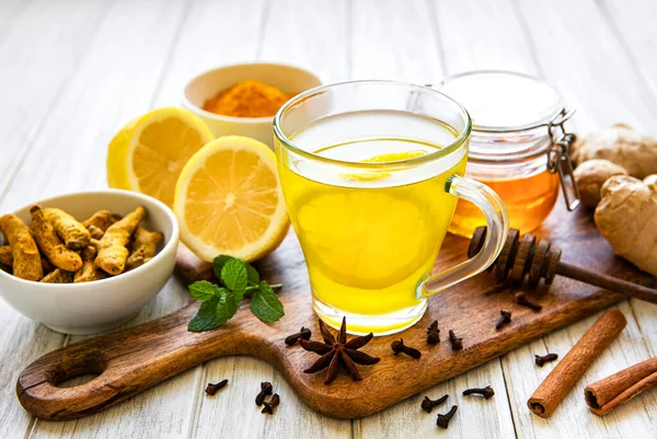 Beyaz ahşap arka planda zerdeçal, zencefil, limon ve bal içeren enerji toniği