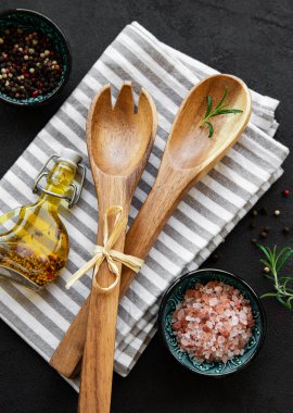 Eski mutfak gereçleri. Tahta kaşıklar, kesim tahtası, peçete ve baharatlar siyah arka planda. Üst görünüm