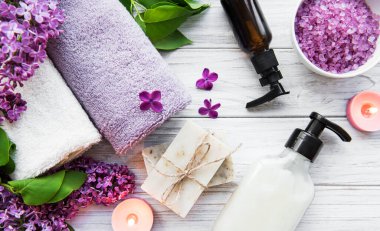 Leylak çiçekli spa seti. Kasede deniz tuzu, aroma yağı şişeleri ve ahşap arka planda mumlar.. 