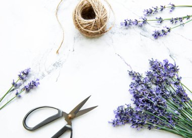 Beyaz mermer arka planda lavanta çiçekleri, makas ve ip