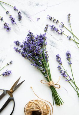 Beyaz mermer arka planda lavanta çiçekleri, makas ve ip