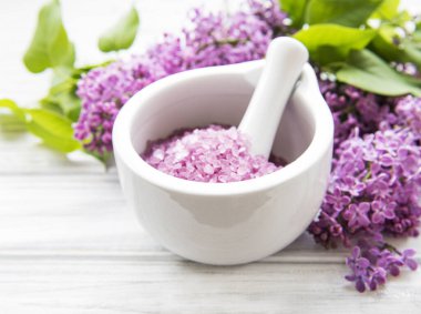 Beyaz ahşap bir arka planda havan ve leylak çiçekli spa deniz tuzu