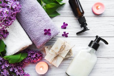 Leylak çiçekli spa seti. Kasede deniz tuzu, aroma yağı şişeleri ve ahşap arka planda mumlar.. 