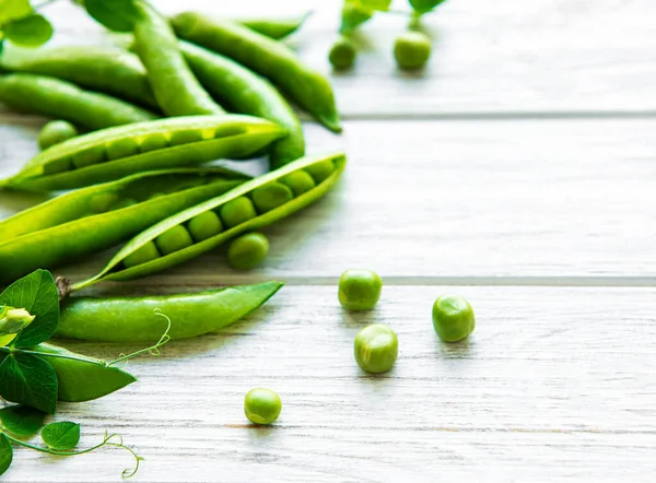 白い木の背景に緑のエンドウ豆 健康食品の背景 — ストック写真