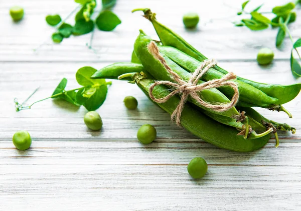 白い木の背景にエンドウ豆の葉を持つ緑のエンドウ豆のポッド 有機食品 — ストック写真