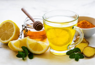 Beyaz mermer bir zemin üzerinde zerdeçal, zencefil, limon ve bal içeren enerji toniği