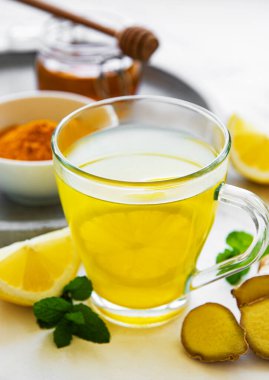 Beyaz mermer bir zemin üzerinde zerdeçal, zencefil, limon ve bal içeren enerji toniği