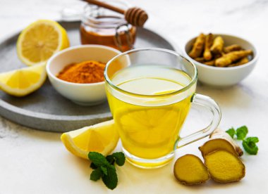 Beyaz mermer bir zemin üzerinde zerdeçal, zencefil, limon ve bal içeren enerji toniği