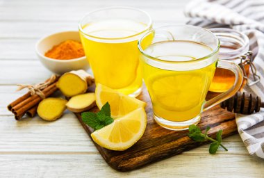 Beyaz mermer bir zemin üzerinde zerdeçal, zencefil, limon ve bal içeren enerji toniği