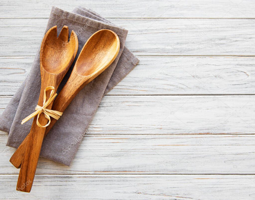 Two wooden salad spoons  and napkin on a wooden background, flat lay