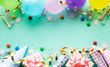 Mutlu yıllar ya da parti geçmişi. Doğum günü balonları, konfeti ve pastel yeşil arka planda kurdeleler. Üst Manzara. Boşluğu kopyala.
