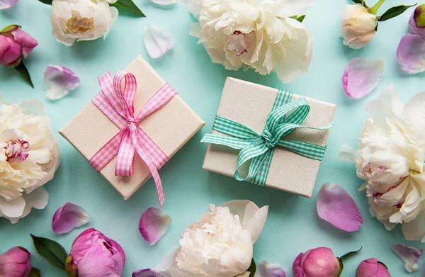 Mavi pastel arka planda şölen kompozisyonu: şakayık çiçekleri, hediye kutuları. Üst görünüm, alanı kopyala.