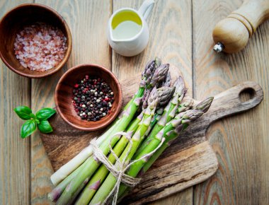 Köy ahşap bir masada taze yeşil kuşkonmaz demeti.