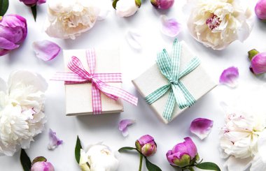 Beyaz arka planda şölen kompozisyonu: şakayık çiçekleri, hediye kutuları. Üst görünüm, alanı kopyala.