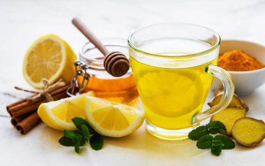 Beyaz mermer bir zemin üzerinde zerdeçal, zencefil, limon ve bal içeren enerji toniği