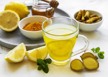 Beyaz mermer bir zemin üzerinde zerdeçal, zencefil, limon ve bal içeren enerji toniği