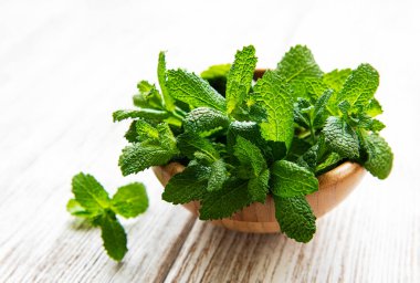 Eski ahşap masanın üzerinde bir demet taze nane ile bir kase. Sağlıklı beslenme kavramı.