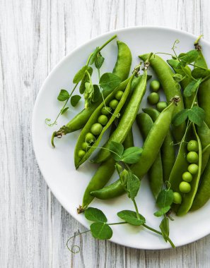 Beyaz ahşap bir zeminde yeşil bezelyeler. Yukarıdan görüntüle.