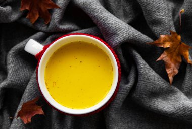 Beyaz bardakta altın süt. Sonbahar yaprakları. Süt, zerdeçal, tarçın ve baldan yapılmış sağlıklı bir içecek..