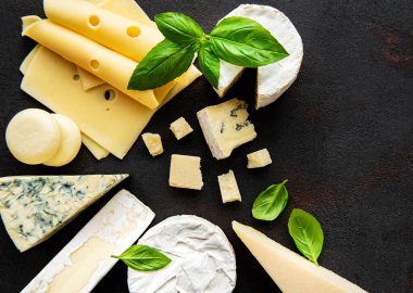 Siyah beton arka planda çeşitli peynir türleri