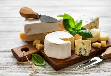 Beyaz ahşap arka planda çeşitli peynir çeşitleri