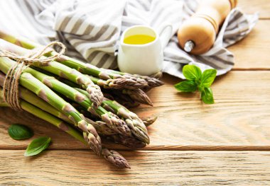 Köy ahşap bir masada taze yeşil kuşkonmaz demeti.