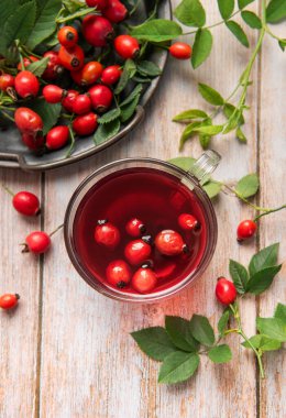 Taze gül kalçalı bir bardak sıcak gül suyu, sağlıklı ve lezzetli bir içeceğin tadını çıkarıyor.