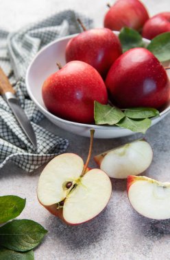 Kırmızı elmalar ve kesilen elma parçaları taş bir yüzey üzerinde bir bıçakla