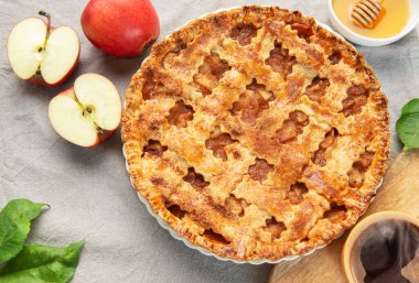 Taze pişmiş elmalı turta yanında bal ve sıcak bir sonbahar sahnesi oluşturan bir fincan buharlı kahve.