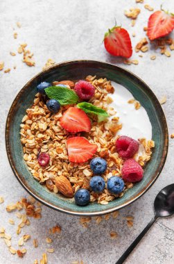 Sağlıklı bir kahvaltı için yoğurt, taze böğürtlen, badem ve nane ile dolu granola kasesi.