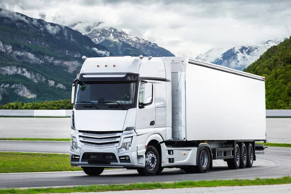 Dağ yolunda konteyner yüklü kargo kamyonu. Konsept: kargo yolu taşımacılığı, kamyon teslimatı, lojistik teması, ücretsiz logo 