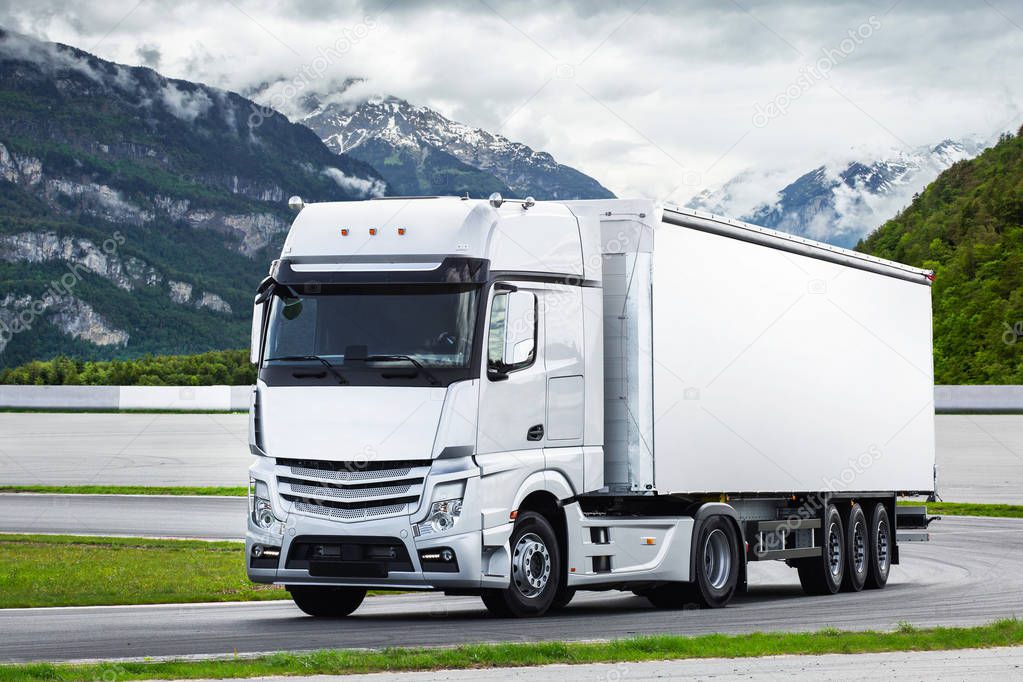 Loaded cargo truck with container on mountain road. Concept: cargo road transportation, truck delivery, logistics theme, logo free