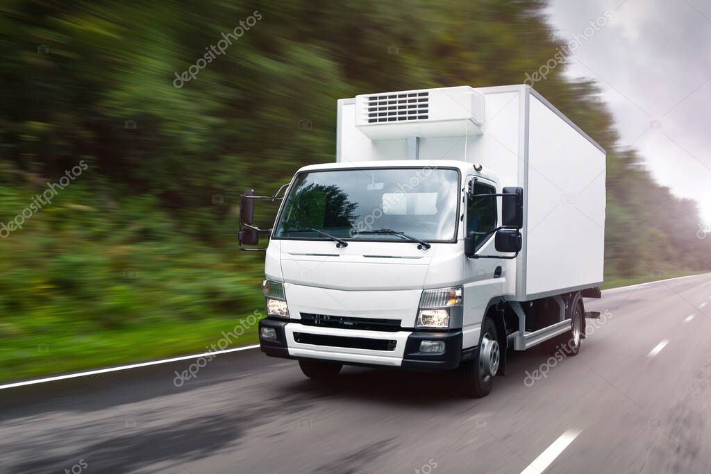 White delivery truck moving on the road. Concept: cargo road transportation, truck delivery, moving, logistics theme, logo free