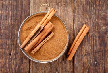 Tarçın çubukları ve ahşap masa üzerinde toz. Üstte görüntü.