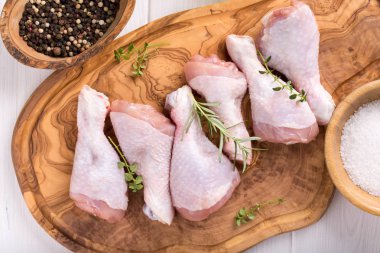 Kesme tahtası üzerinde çiğ tavuk sopaları. Pişmemiş tavuk budu. Üstten görünüm.