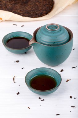 Mavi Çaydanlık ve iki küçük bardak puer çay beyaz tablo dolu. Preslenmiş Çince Pu-erh çay fermente.