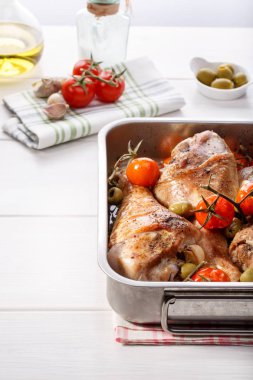 Kiraz domates, yeşil zeytin ve sarımsak ile kavrulmuş Türkiye baget. Beyaz masa üzerinde tava pişirme ızgara hindi budu.