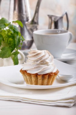 Lezzetli tartlets beze üstüne ile. Kahve ve kek beyaz masaya servis.