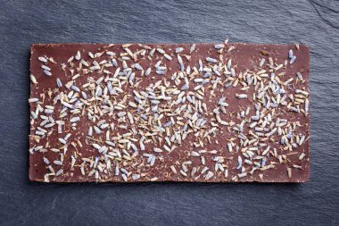 Kurutulmuş lavanta çiçekleri koyu zemin üzerine koyu çikolata bar. Üstten görünüm.