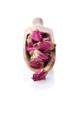 Kuru kırmızı gül tomurcukları ahşap Kepçe üzerinde yakın çekim. Sağlıklı bitki çayı Isolated beyaz arka plan üzerinde. Seçici odak. 